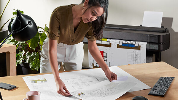 Lady working with a HP DesignJet and looking at some technical prints.